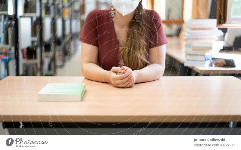 Woman sitting at table in library with mask Library Mask Book Reading Study Education Know Academic studies Literature School Information Wisdom