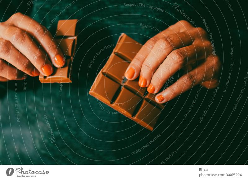 A woman breaks off a row from a chocolate bar Woman Chocolate nibble hands Brown Candy candy Chocolate bar