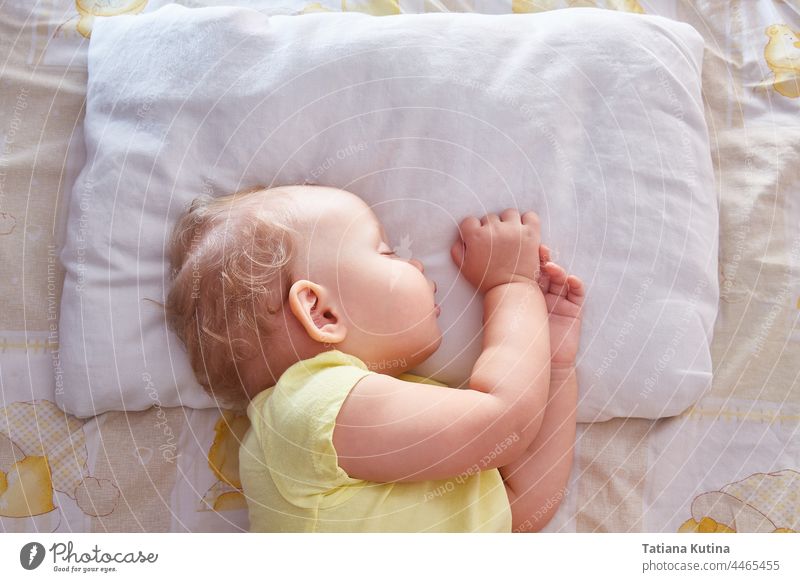 The baby sleeps on its side on a white pillow. beautiful sweet dream cute childhood bed face little toddler adorable young blanket asleep head kid bedtime