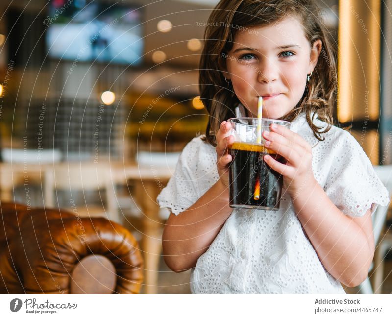 Smiling girl drinking refreshing drink in cafe carbonate soft drink refreshment soda glass cold straw sweet thirst beverage charming childhood delicious smile