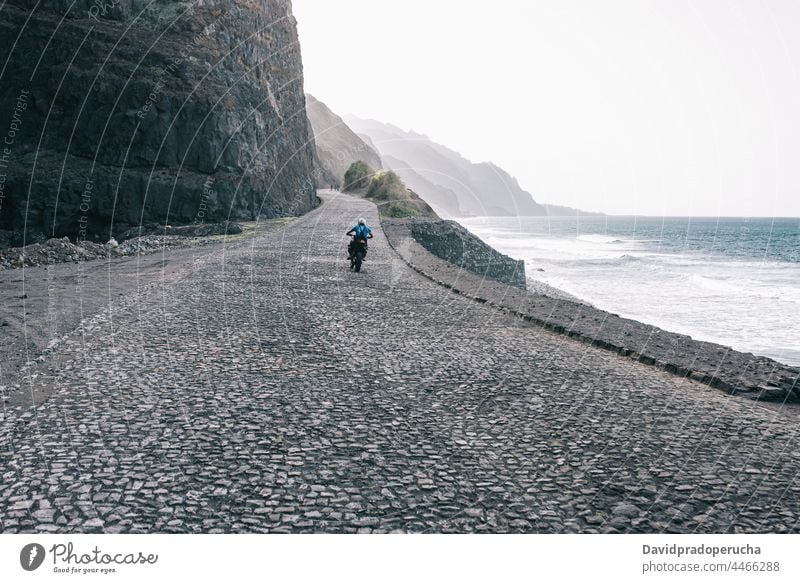 Faceless person riding motorbike on deserted road traveler motorcycle ride sea mountain trip santo antao cape verde cabo verde africa adult sit enjoy speed
