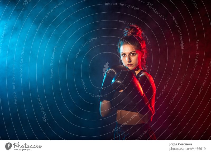 Young woman doing boxing training at the gym, she is wearing boxing gloves boxer female focus fit athlete sportswear workout challenge equipment concentration