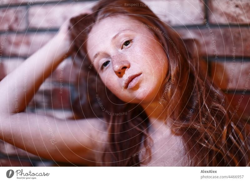 Young redhead freckled woman holds her long hair up back and looks sideways at camera Red-haired Long-haired Freckles portrait red blonde Magic wand Definitive