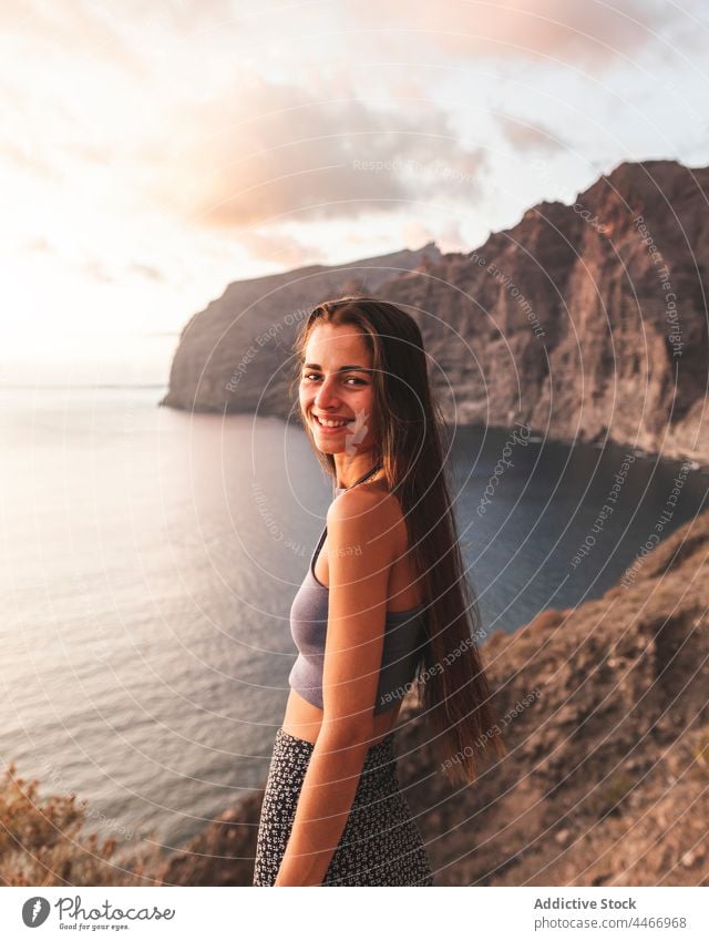 Happy woman touching hair on mount against sea at sunset mountain sky nature highland landscape horizon endless evening massive magnificent cliff ocean cloudy