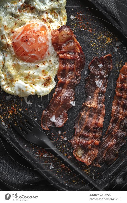 Delicious fried egg and bacon strips with spices breakfast food nutrition delicious cutlery tray fabric appetizing slice natural palatable condiment ingredient