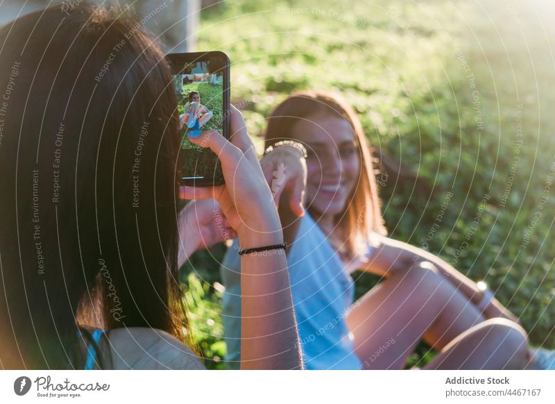 Crop teen taking photo of girlfriend on smartphone in park best friend take photo smile holding hands spend time moment touch screen using cellphone memory