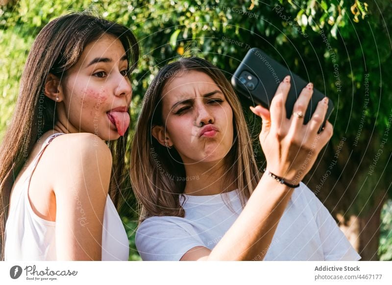 Girlfriends grimacing while taking selfie on smartphone in park girlfriend grimace having fun moment memory friendship using gadget best friend spend time