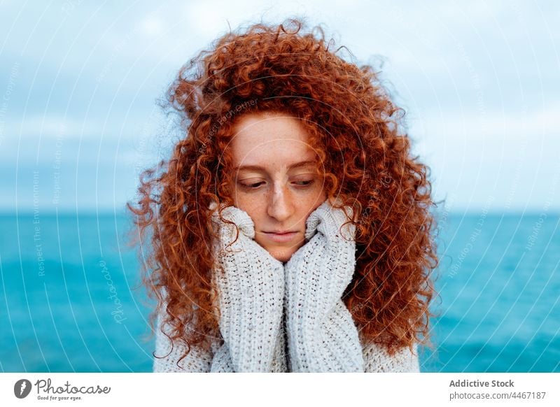 Unhappy woman looking down on seashore personality individuality female portrait long hair delight knitted ginger hair seaside red hair traveler redhead sweater