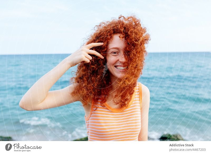 Cheerful woman standing on seashore happy blue wind glad vacation holiday delight female cheerful long hair redhead water nature optimist ginger hair positive