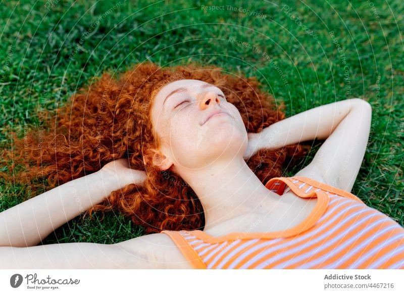 Cheerful woman with hands behind head lying on grass happy relax individuality lawn chill enjoy delight pleasure female cheerful appearance glad optimist