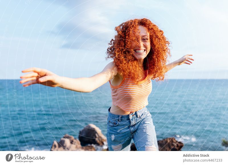 Carefree woman dancing on hill in seashore dance enjoy move energy coast freedom happy expressive female smile outstretched arms run nature travel flying hair
