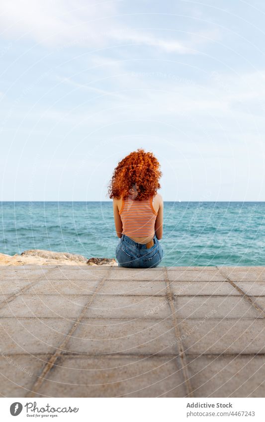 Red haired woman admiring rippling sea from coast admire freedom trip embankment relax holiday horizon female seafront seascape seacoast redhead ginger stone
