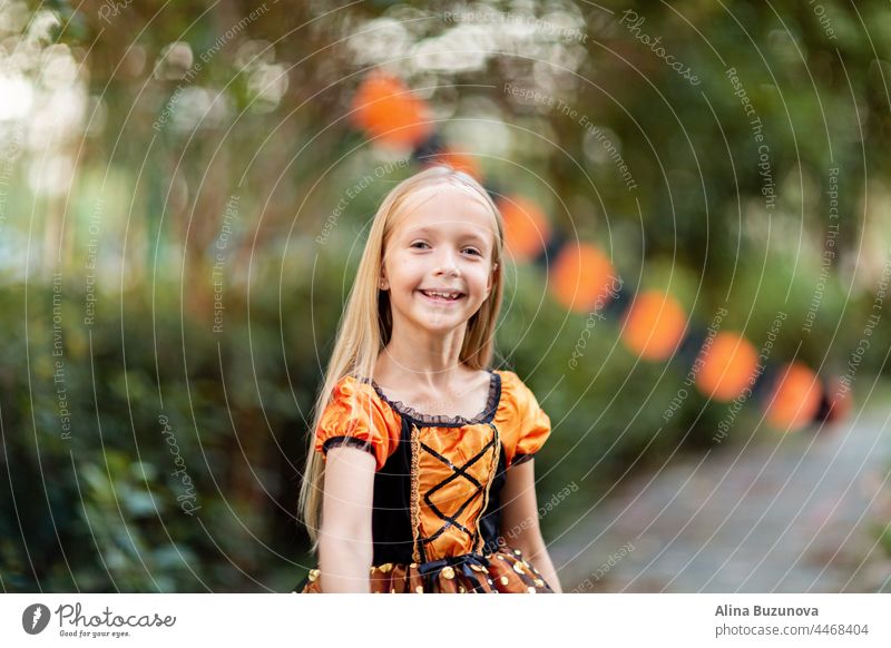 Little Caucasian Girl in costume of which orange and black color and celebrating Halloween outdoor halloween witch hat child girl celebrate Scary kid person