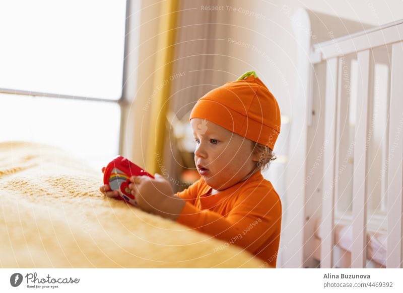 Happy baby one year old in orange Halloween costume at home halloween cry gas health newborn care skin child pumpkin trick or treat autumn cute kid girl holiday