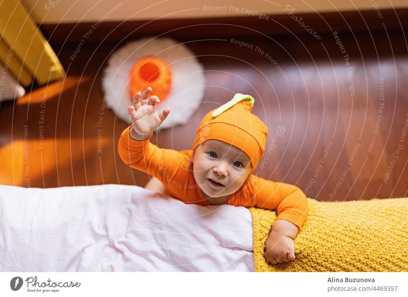 Happy baby one year old in orange Halloween costume at home halloween cry gas health newborn care skin child pumpkin trick or treat autumn cute kid girl holiday