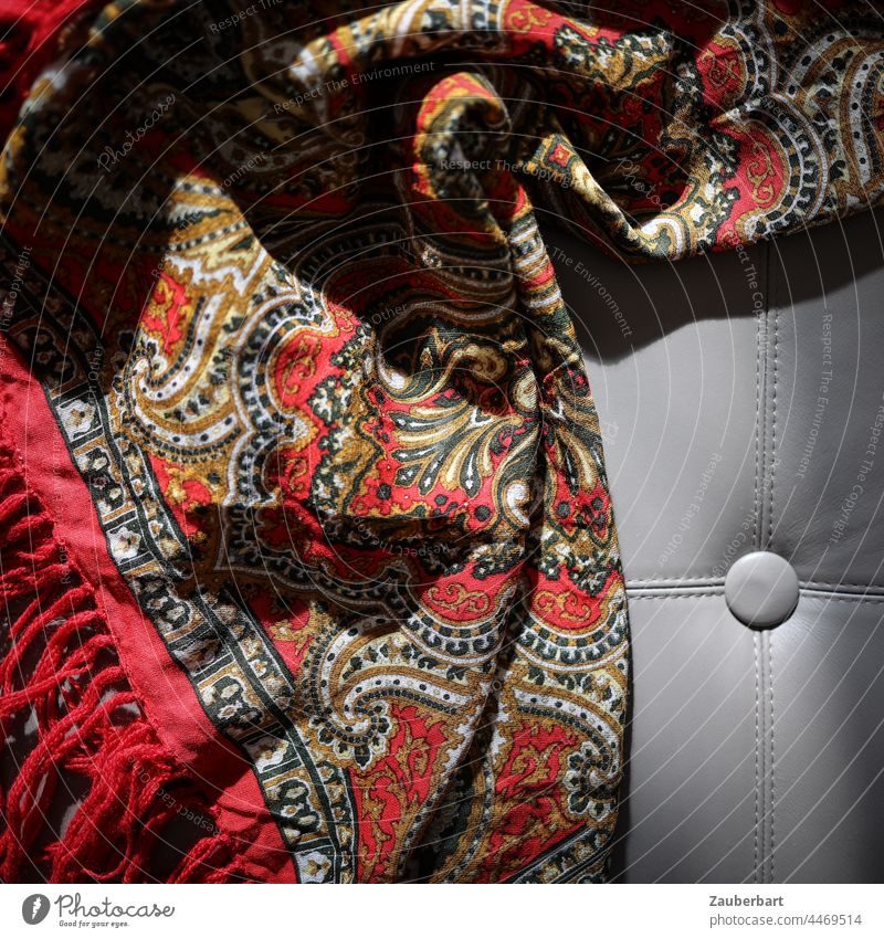 Folded red blanket with paisley pattern in sunlight on leather upholstery Blanket Sunlight crease Folds Shadow Bolster Structures and shapes Cloth Pattern