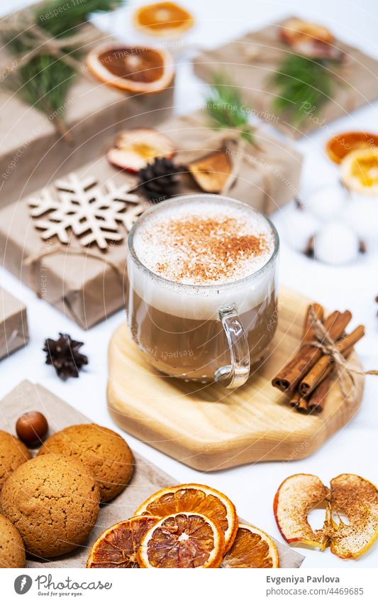 Cup of Latte Coffee with Cinnamon and Christmas presents, decorated dried fruits, pine cones and fir branches. Cozy winter holiday background. advertising aroma