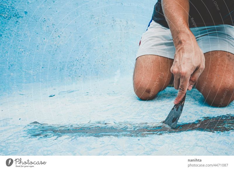 Close up of a man fixing the floor of a pool maintenance crack diy putty putty knife palette palette knife work job home craft hard hard work physical strong