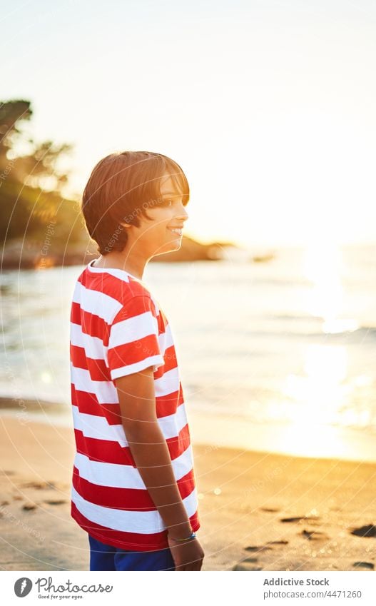 Pensive boy standing on wet sandy beach at bright sunset kid sea wave shore sundown vacation thoughtful coast nature water seaside seashore child seascape