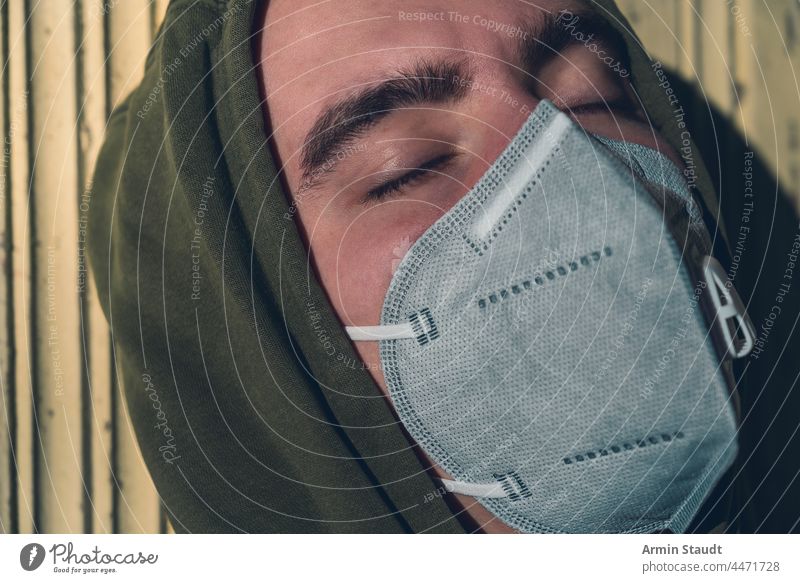portrait of a young man wearing a FFP3 corona mask with his eyes closed in the sun beautiful breath care casual caucasian closed eyes confident cool