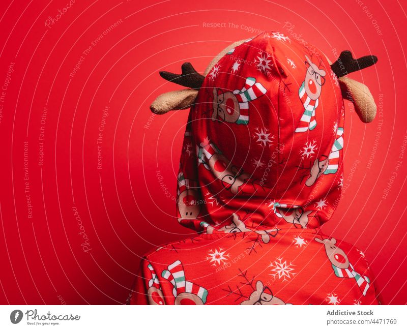 Anonymous kid standing in red studio during Xmas holiday child christmas pajama funny childhood celebrate winter deer tradition xmas innocent new year adorable