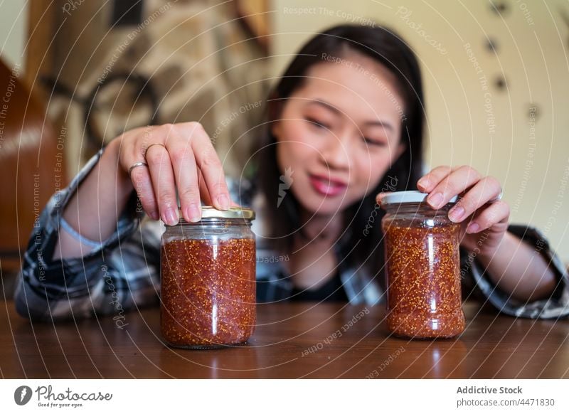 Asian woman with jars of fig jam at home sweet treat natural organic delicious homemade fruit tasty house marmalade yummy transparent lid glass asian ethnic