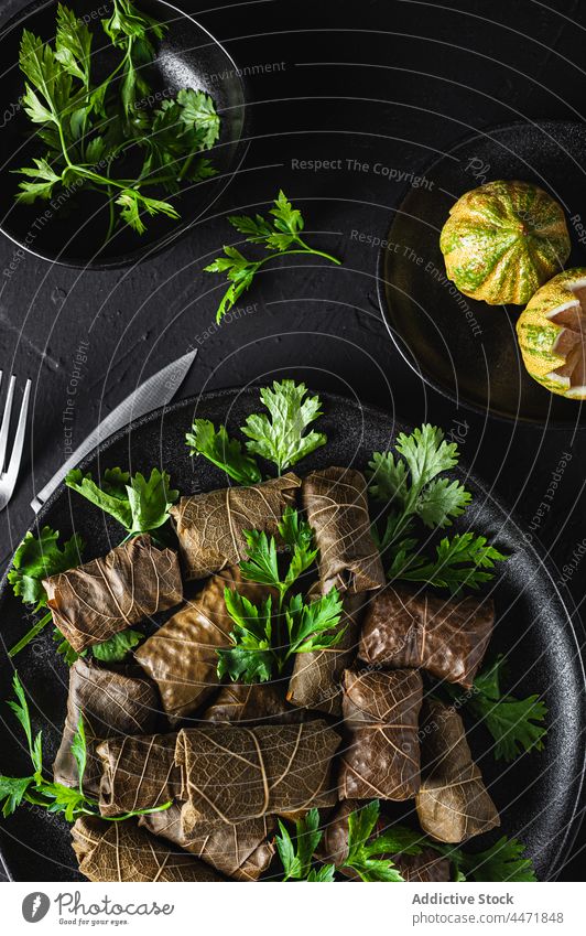 Plate with delicious sarma dish with parsley and lemon fork knife palatable dolma meat grape leaves tasty cuisine ingredient citrus dinner meal fresh