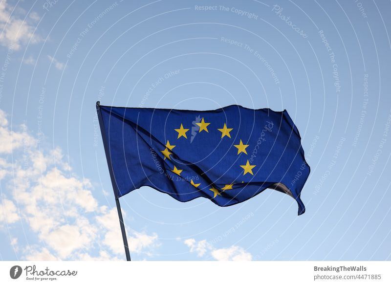 European Union EU flag waving in clear blue sky Flag flying wave wind flagstaff flagpole closeup side view stars symbol patriotic patriotism political official