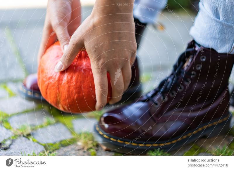 Close-up of a young woman's hands and boots lifting an orange pumpkin. active more adult Autumn background body part Boots concept Day Decoration Detail To fall