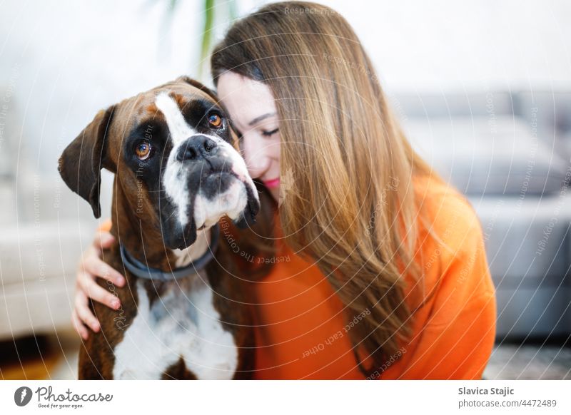 Young woman hugging her German boxer dog sitting on sofa Blonde Woman kind Love of animals observantly Beauty & Beauty Warmth Pet Dog Girl Smiling Lifestyle