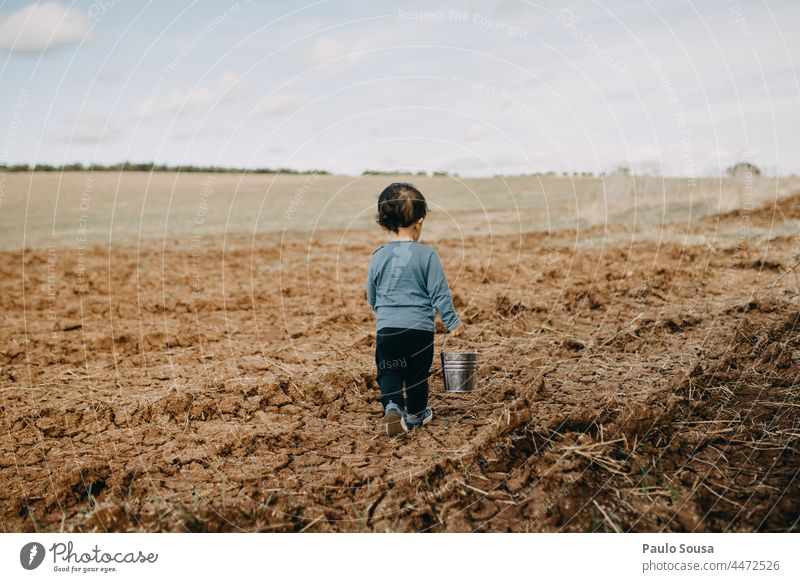 Rear view child walking with bucket through fields Child childhood Caucasian one one person Autumn Authentic Cute Lifestyle Joy Happy caucasian kid Infancy