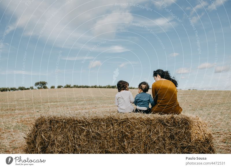 Mother sitting with children on hay bale Hay Hay bale Mother with child motherhood Child childhood Field fields Autumn togetherness Happy Love Parents