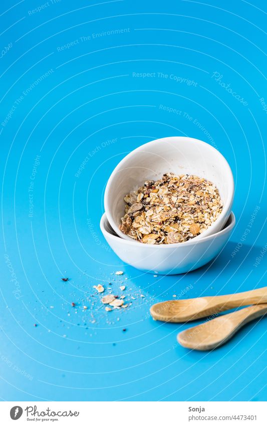 Breakfast cereal in two bowls on a blue background. Cereal Blue Neutral Background Spoon Food Oat flakes Dried Diet Nutrition Healthy Organic naturally Bowl