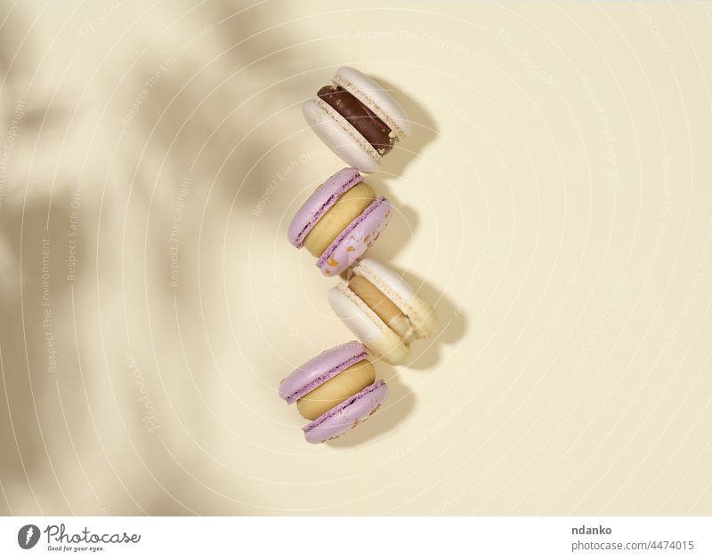baked macarons with different flavors on a beige background, top view shadow almond assorted bakery biscuit cake confection confectionery cookie cream delicious