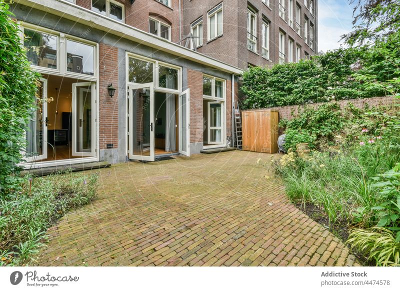 Courtyard of residential house with assorted cultivated plants courtyard exterior architecture facade garden bloom porch cottage brick wall dwell suburb foliage