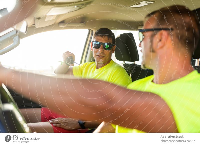 Man driving with colleague talking on walkie talkie men lifeguard drive car work safety connection service male sunglasses occupation vehicle job speak