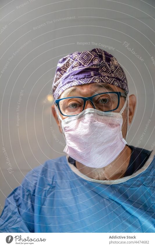 Senior doctor in surgical suit and mask in clinic man surgeon medicine old professional operation portrait occupation treat male hospital surgery hat