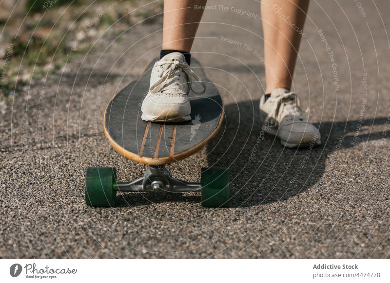 Anonymous woman riding longboard on asphalt road ride activity hobby enjoy leisure nature balance female cloudy training hill carefree active practice energy