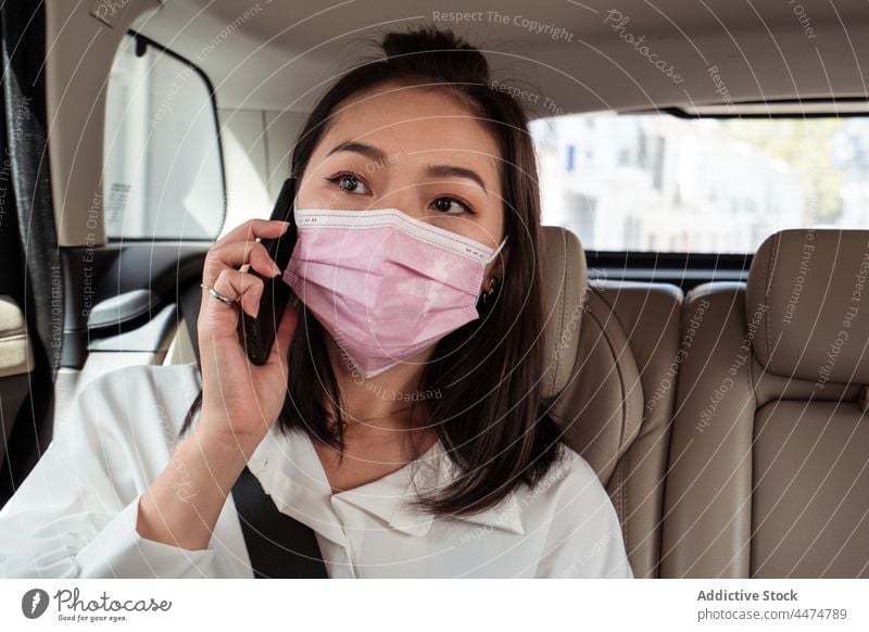 Asian woman talking on smartphone on backseat in taxi passenger using mask service covid19 female new normal commute car covid 19 coronavirus asian ethnic