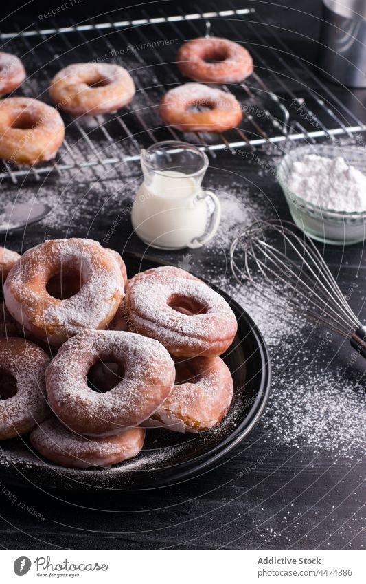 Delicious doughnuts with powdered sugar fried dessert sweet pastry calorie confectionery milk plate rack messy food treat table serve tasty delicious yummy