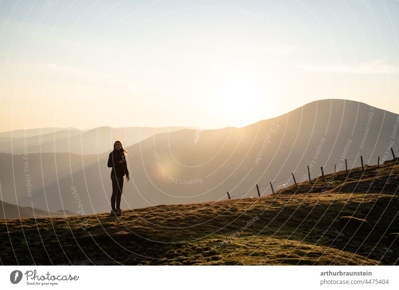 Young woman with long hair and camera looking for motive at sunrise on mountain mountains mountain panorama Movement out Photography Take a photo Freedom