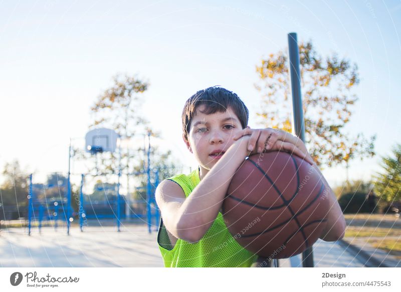 Young teen male with sleeveless standing on a street basket court while smiling at camera basketball player real teenage youth boy fit happy game people active