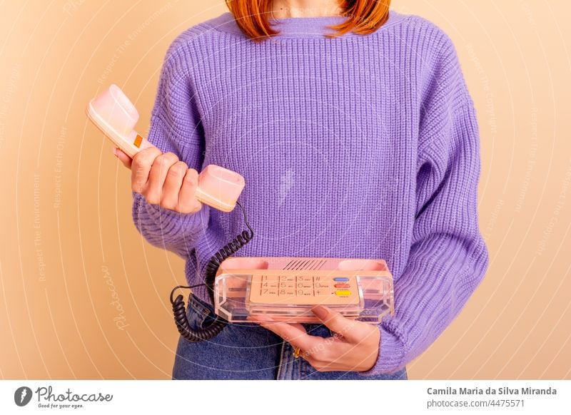 Woman in lilac sweater, jeans and socks holding a phone. Beige background. beige business call casual classic communication fashion fun girl hand lifestyle