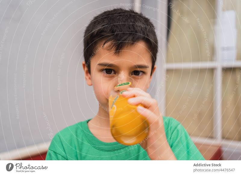 Boy drinking juice from glass boy kid beverage thirst childhood refreshment sweet room home serious light thoughtful domestic style calm casual cute confident