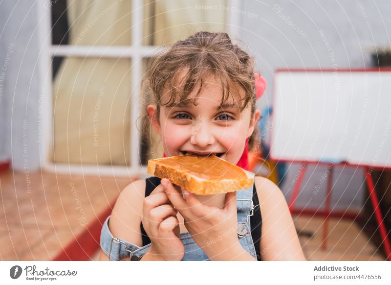 Girl eating bread with jam girl kid food childhood snack appetite bite hungry light room adorable cute tasty yummy delicious sweet fresh home edible appetizing