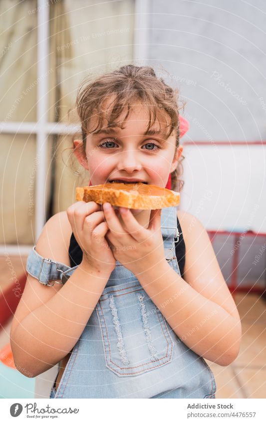 Girl eating bread with jam girl kid food childhood snack appetite bite hungry light room adorable cute tasty yummy delicious sweet fresh home edible appetizing