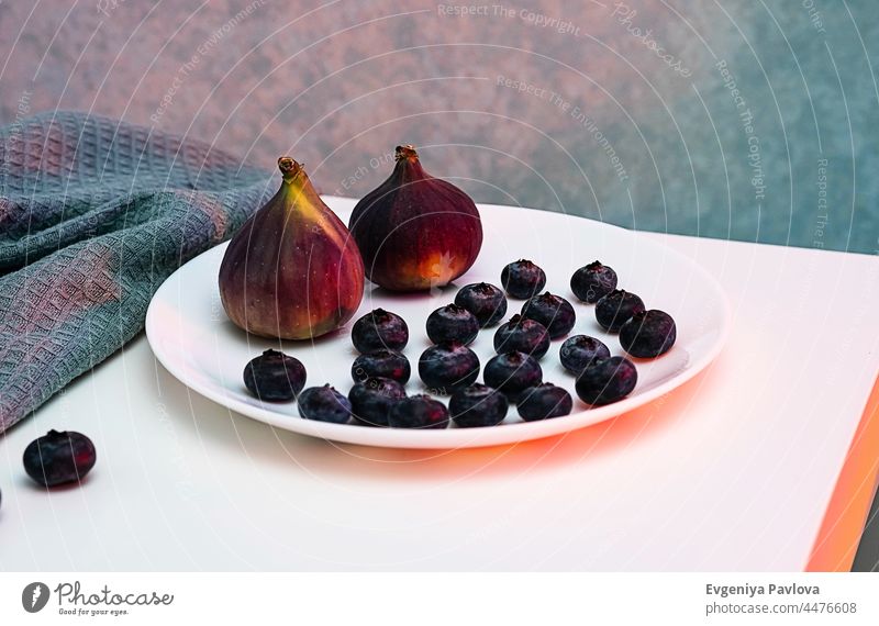 Figs and blueberries on white plate in neon lighting. Modern minimalist still life, copy space. agriculture antioxidant background berry bilberry bio blueberry