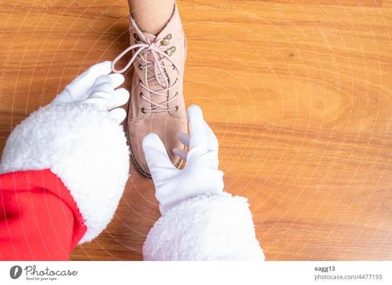 Santa Claus is helping a girl tie her shoelaces assistance bonding casual child childhood claus close up day encouragement family fatherhood foot footwear