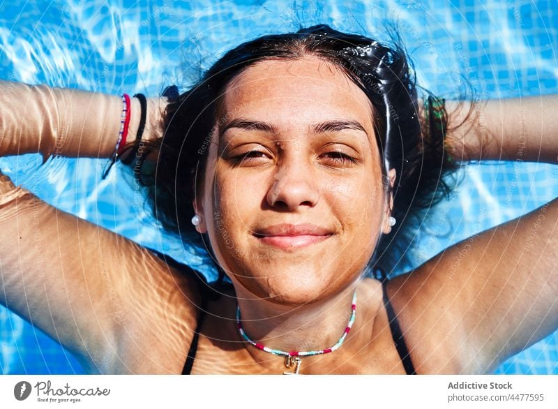 Attractive woman in swimsuit in pool water bikini summer resort vacation sunlight poolside charming young hispanic ethnic female holiday aqua rest swimwear