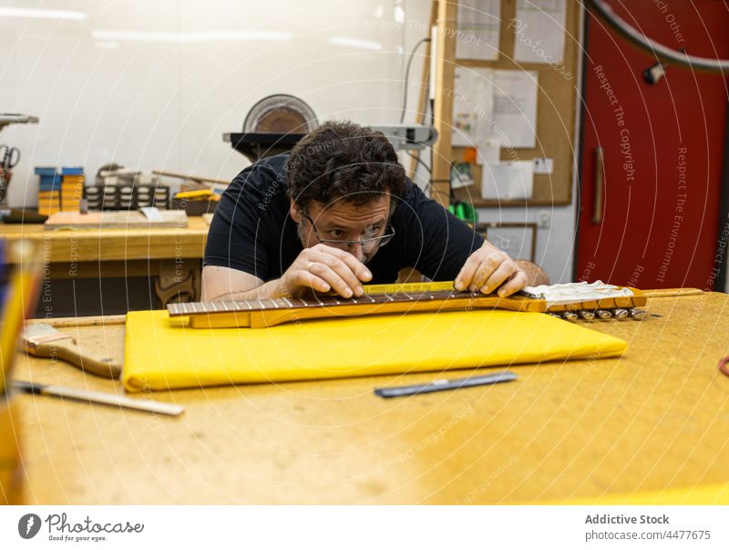 Professional master measuring guitar neck in studio craftsman instrument professional measure occupation frets workshop handicraft concentrate focus workplace